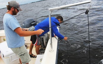 Researchers on a boat, taking water samples.